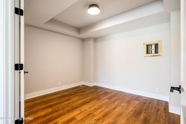 empty room featuring hardwood / wood-style flooring and a raised ceiling