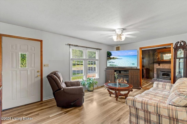 living room featuring a textured ceiling, light hardwood / wood-style flooring, and ceiling fan