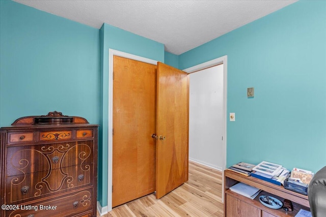 hallway featuring light wood-type flooring and a textured ceiling