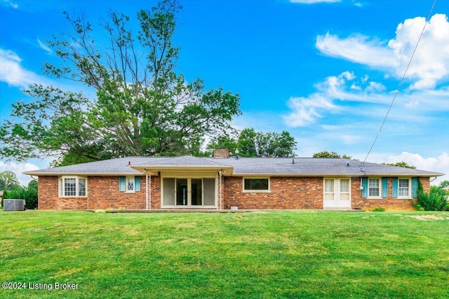 rear view of property with a yard, french doors, brick siding, and a chimney