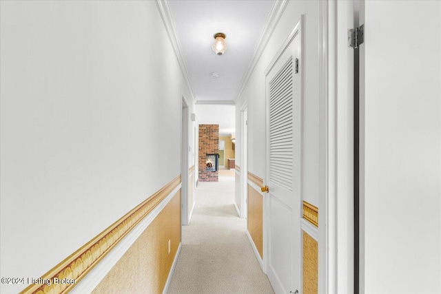 corridor with light carpet, a wainscoted wall, and ornamental molding