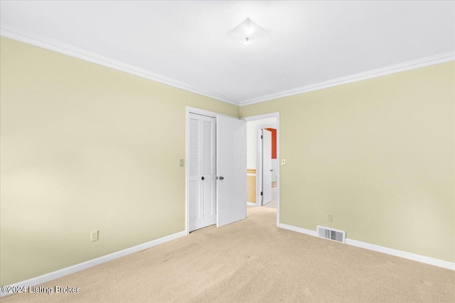 spare room with visible vents, light colored carpet, baseboards, and ornamental molding