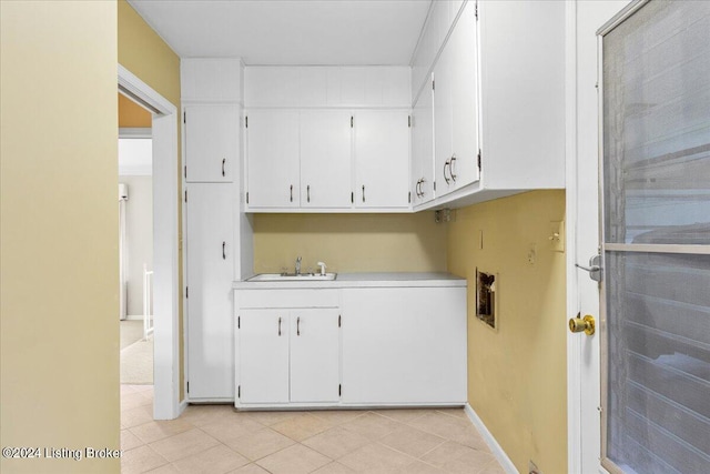 laundry room featuring baseboards, washer hookup, light tile patterned floors, cabinet space, and a sink