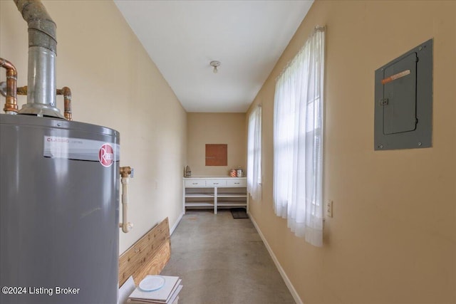 hall featuring electric panel, baseboards, water heater, and finished concrete floors