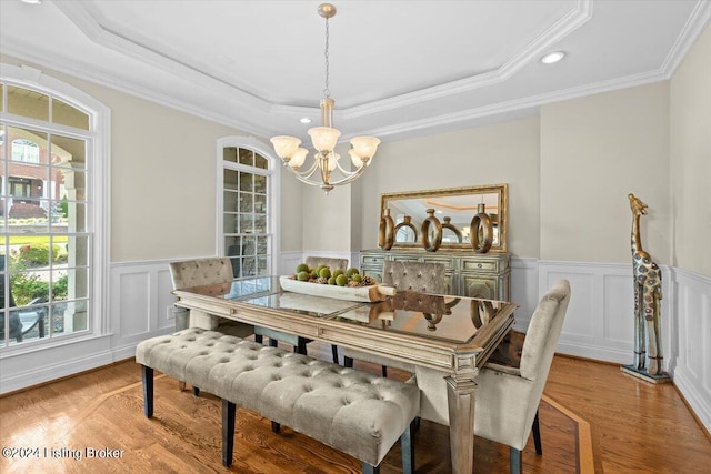 dining room featuring a tray ceiling, hardwood / wood-style flooring, a chandelier, and ornamental molding