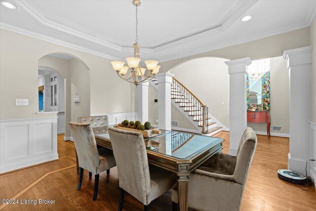 dining room featuring ornamental molding, hardwood / wood-style floors, an inviting chandelier, and ornate columns