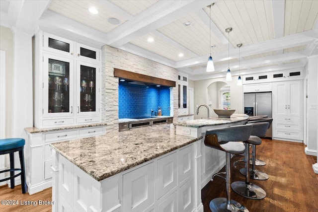 kitchen featuring a spacious island, decorative light fixtures, dark wood-type flooring, beam ceiling, and white cabinets