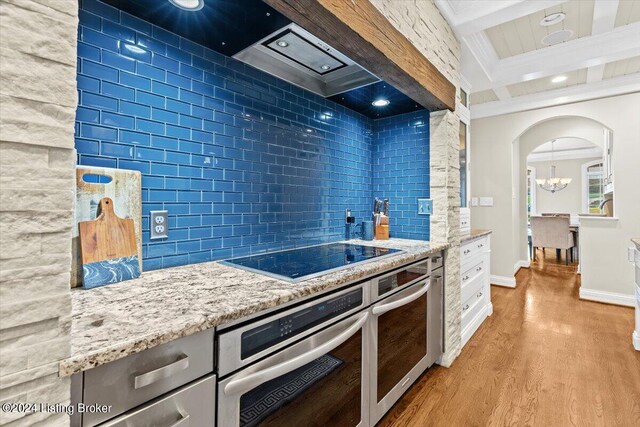 kitchen with oven, tasteful backsplash, black electric cooktop, light stone counters, and light wood-type flooring