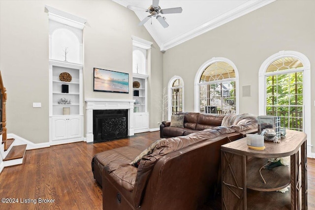 living room with dark hardwood / wood-style floors, built in features, crown molding, high vaulted ceiling, and ceiling fan