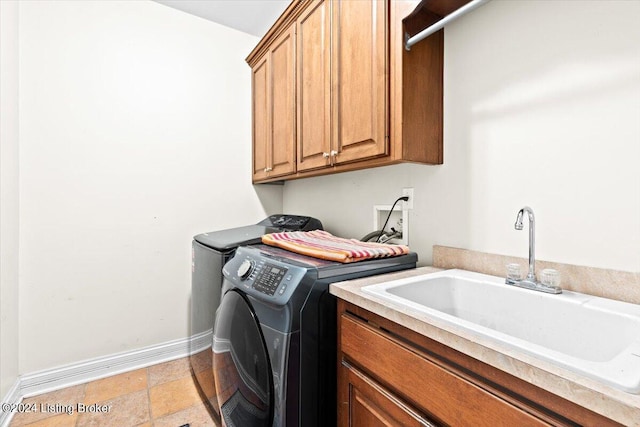 laundry area featuring stone finish flooring, baseboards, washer and dryer, cabinet space, and a sink