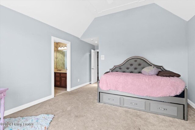 carpeted bedroom with ensuite bath and vaulted ceiling