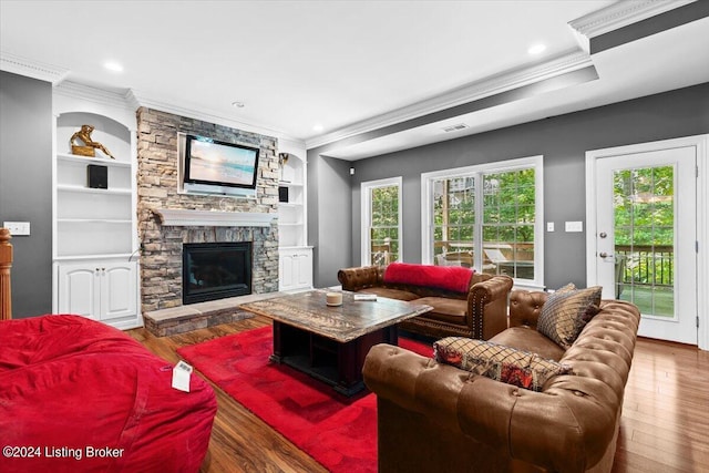 living room with built in shelves, plenty of natural light, wood-type flooring, and a fireplace