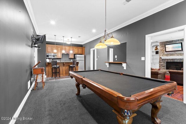 rec room featuring ornamental molding, built in features, pool table, a stone fireplace, and hardwood / wood-style flooring