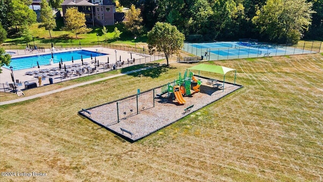 surrounding community with playground community, a yard, and fence