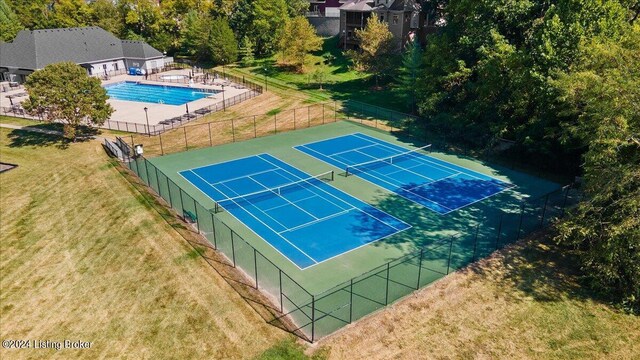 view of tennis court featuring a fenced in pool and a yard