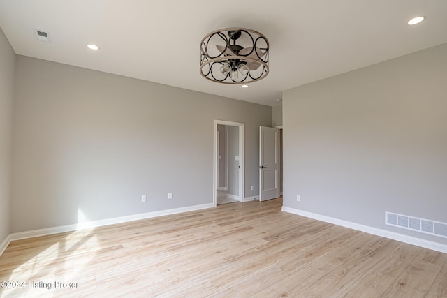 unfurnished room with a notable chandelier and light wood-type flooring