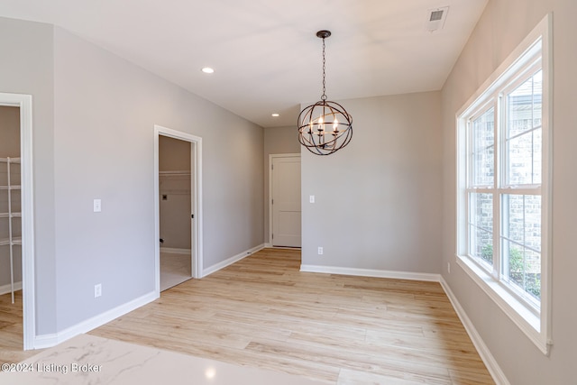 unfurnished room with light hardwood / wood-style flooring, a wealth of natural light, and a notable chandelier