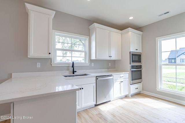 kitchen featuring appliances with stainless steel finishes, white cabinetry, and a wealth of natural light