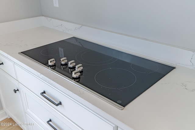 interior details with black electric stovetop and white cabinets