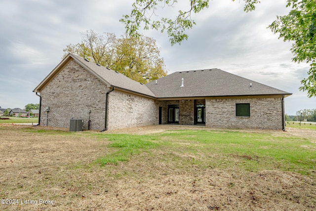 rear view of house featuring a lawn and central air condition unit