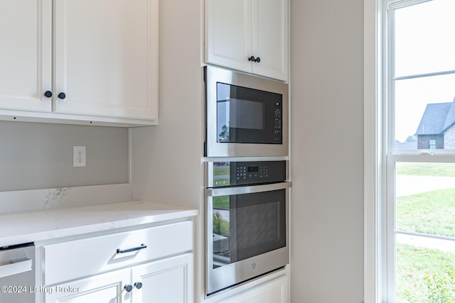 kitchen featuring light stone counters, appliances with stainless steel finishes, and white cabinetry