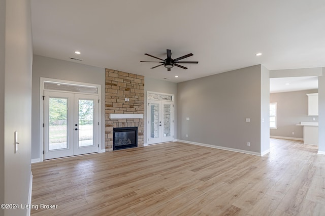 unfurnished living room with light hardwood / wood-style floors, a fireplace, ceiling fan, and french doors