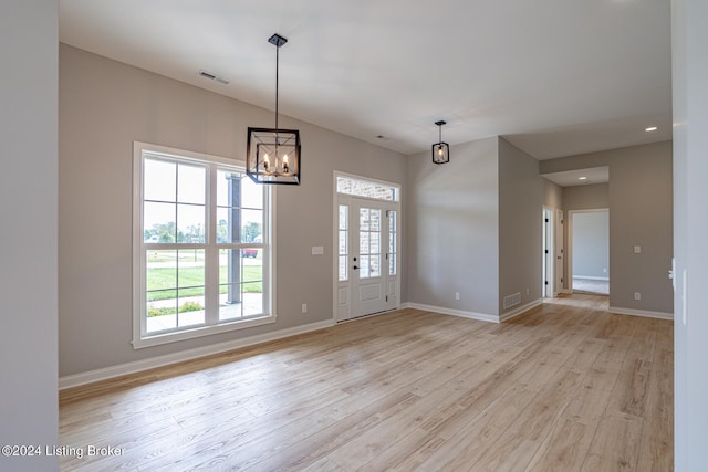 spare room with a chandelier and light hardwood / wood-style floors