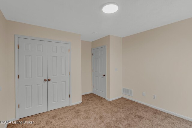 unfurnished bedroom with a closet and light colored carpet