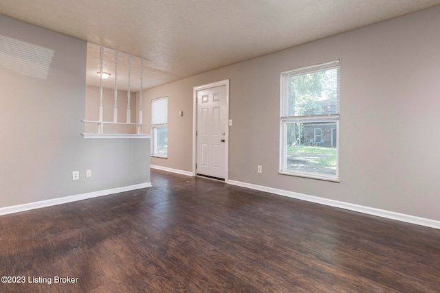 unfurnished living room with a textured ceiling and dark hardwood / wood-style flooring