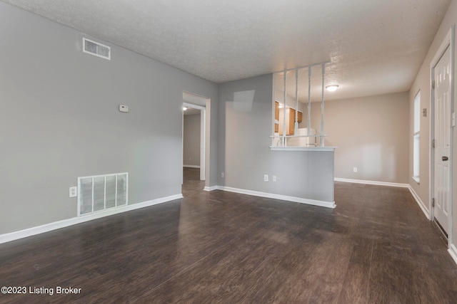 unfurnished living room with a textured ceiling and dark hardwood / wood-style flooring