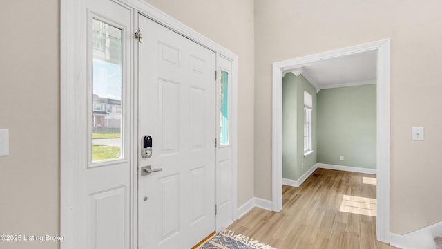 foyer entrance featuring light hardwood / wood-style floors, ornamental molding, and a healthy amount of sunlight