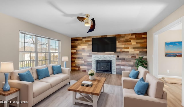 living room featuring wooden walls, ceiling fan, and light hardwood / wood-style floors