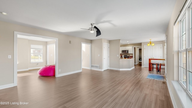 unfurnished living room with wood-type flooring and ceiling fan with notable chandelier