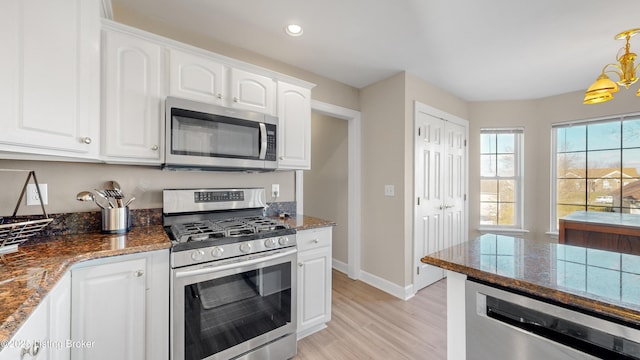 kitchen with stainless steel appliances, light hardwood / wood-style flooring, a notable chandelier, white cabinetry, and hanging light fixtures