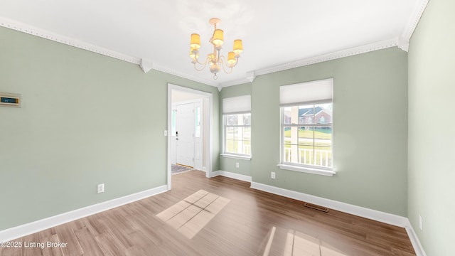 unfurnished room with hardwood / wood-style floors, crown molding, and a chandelier