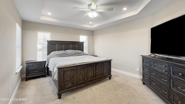 carpeted bedroom with ceiling fan and a tray ceiling