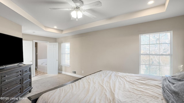 carpeted bedroom with ceiling fan, connected bathroom, and a tray ceiling