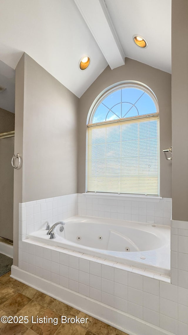 bathroom featuring lofted ceiling and tiled tub