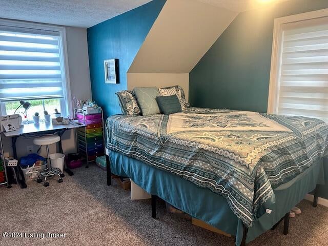 bedroom with a textured ceiling, carpet flooring, and lofted ceiling