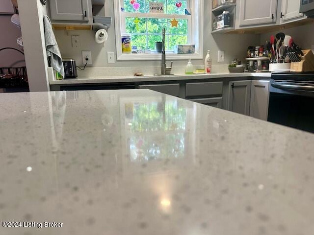 kitchen with electric range, light stone countertops, and sink