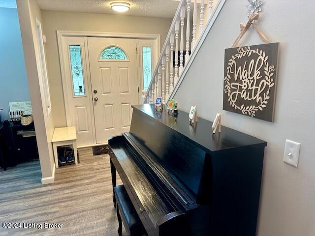 foyer with light wood-type flooring and a textured ceiling