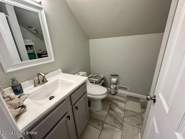 bathroom featuring vanity, toilet, and lofted ceiling