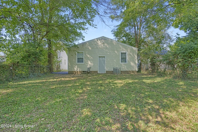 rear view of property featuring cooling unit and a yard