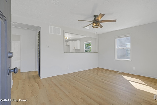 spare room featuring light wood-type flooring, a textured ceiling, and ceiling fan