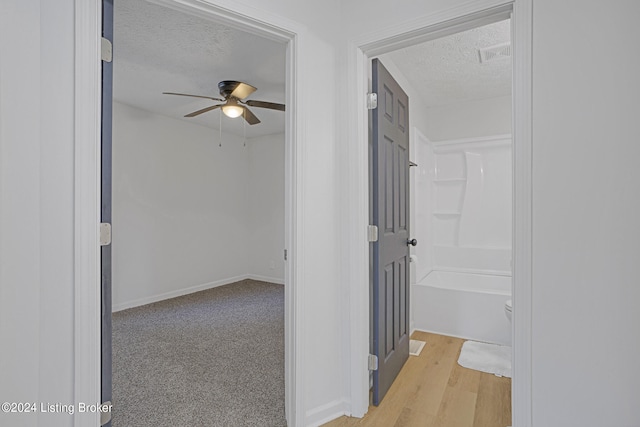 corridor featuring a textured ceiling and light hardwood / wood-style flooring