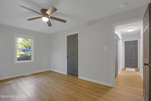 unfurnished bedroom featuring ceiling fan, light hardwood / wood-style floors, and a textured ceiling