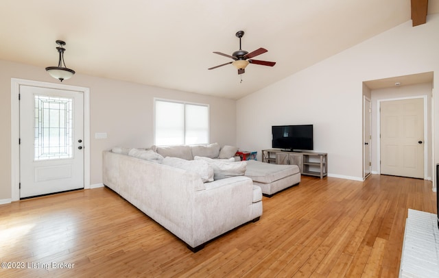 living room with plenty of natural light, light hardwood / wood-style flooring, ceiling fan, and vaulted ceiling with beams