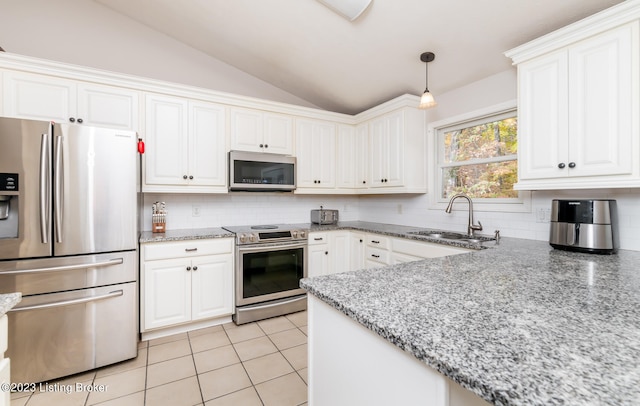 kitchen featuring vaulted ceiling, decorative light fixtures, light tile patterned floors, stainless steel appliances, and sink