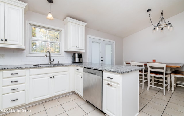 kitchen with decorative light fixtures, light stone counters, sink, lofted ceiling, and stainless steel dishwasher