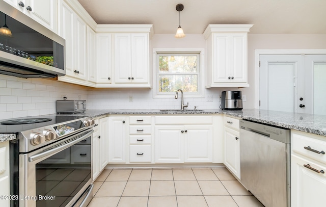 kitchen with hanging light fixtures, light stone countertops, stainless steel appliances, sink, and decorative backsplash